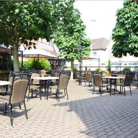Der Sommergarten vom Weinhaus Becker, ausgestattet mit Pflanzen und Essgarnituren aus runden Tischen und Stühlen in Rattanoptik