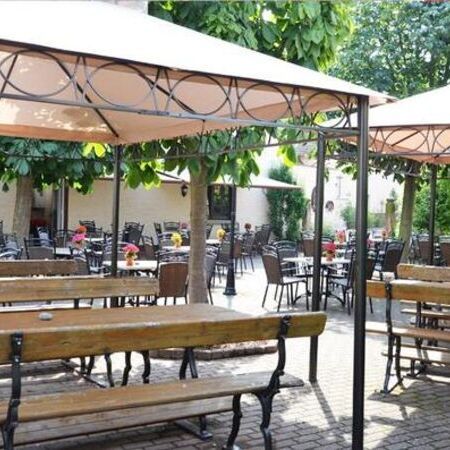 Der Sommergarten vom Weinhaus Becker, ausgestattet mit Pflanzen und Essgarnituren aus runden Tischen und Stühlen in Rattanoptik, Pavillons und Bierzeltgarnituren