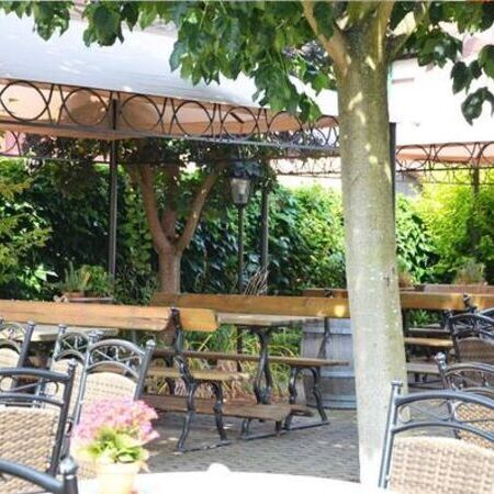 Der Sommergarten vom Weinhaus Becker, ausgestattet mit Pflanzen und Essgarnituren aus runden Tischen und Stühlen in Rattanoptik