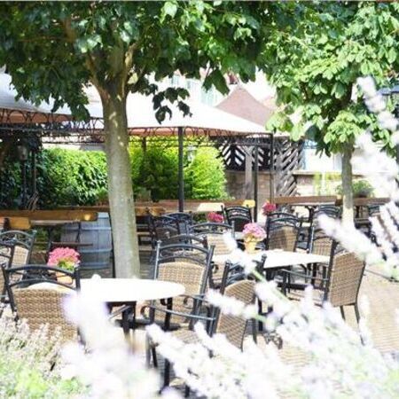 Der Sommergarten vom Weinhaus Becker, ausgestattet mit Pflanzen und Essgarnituren aus runden Tischen und Stühlen in Rattanoptik