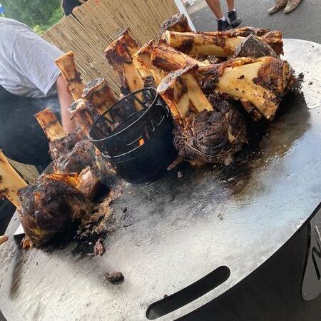 Impressionen - Gegrillte Haxen auf einer Eisenplatte mit Ofen in der Mitte